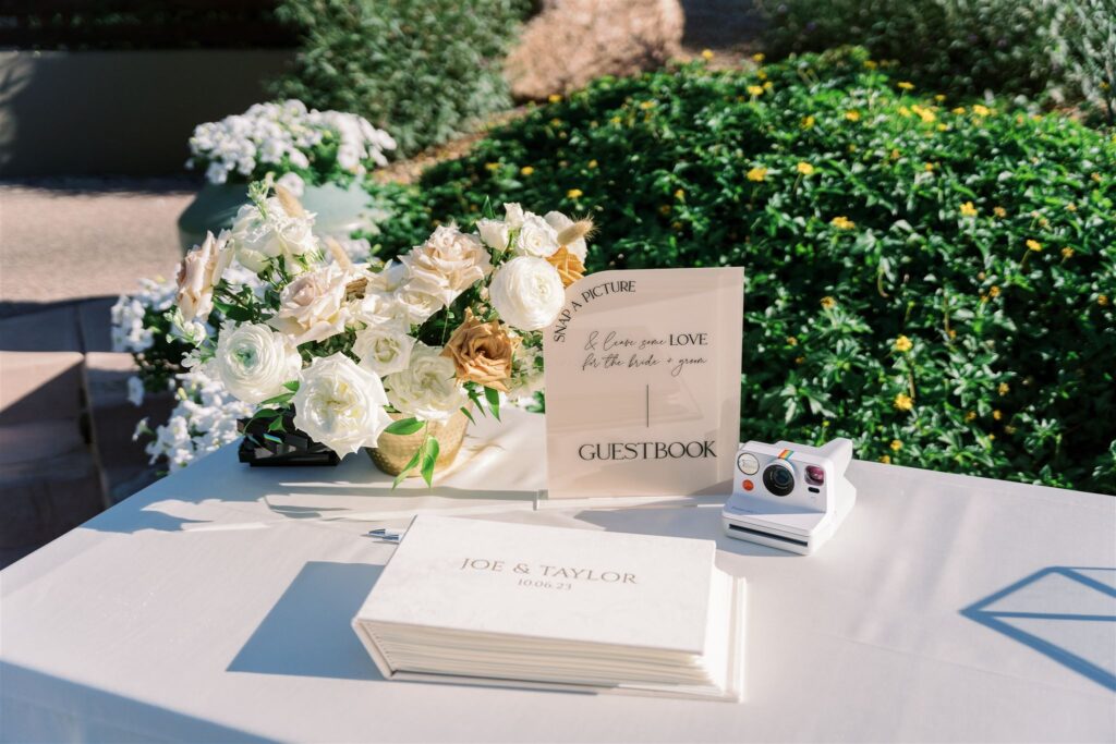 Wedding welcome guest table with guestbook and floral arrangement.