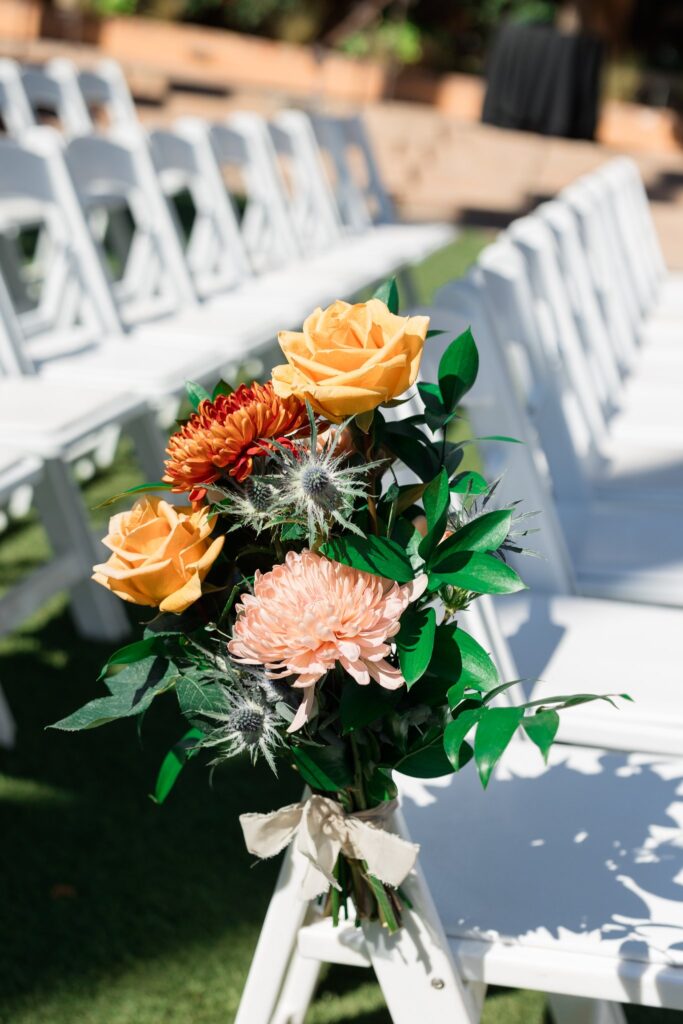 Wedding reception white chair with floral added to outside aisle side.