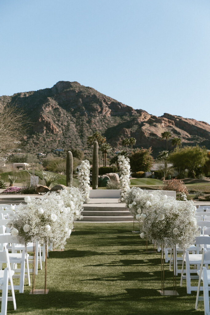 Outdoor wedding ceremony space at Mountain Shadows with tall arrangements on gold stands down the aisle and two floral columns in the altar space.