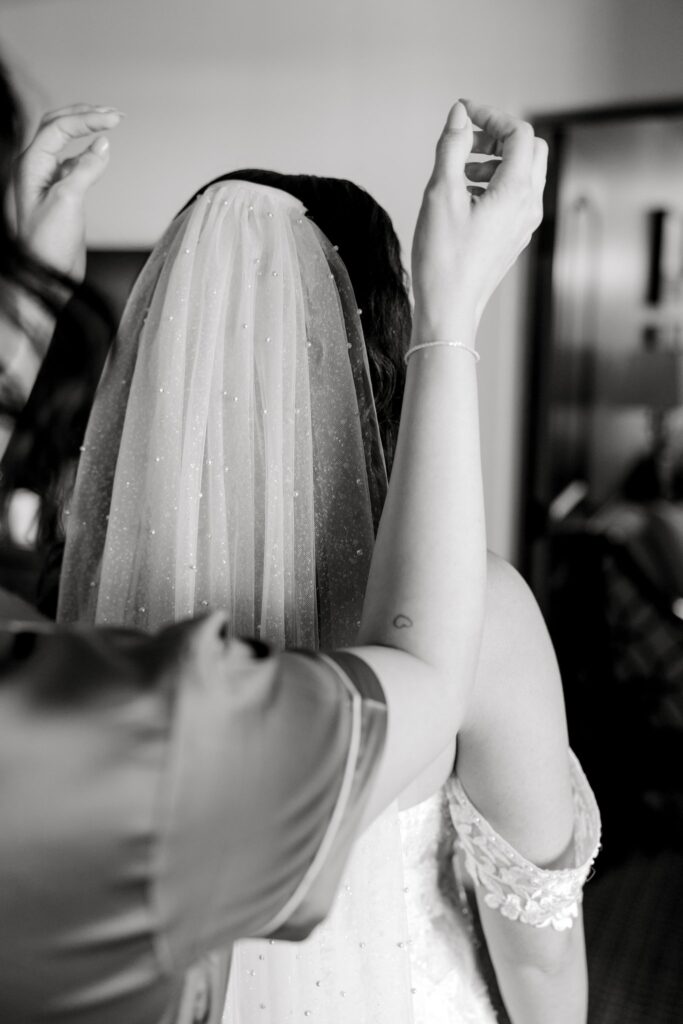 Woman putting bride's veil into the back of her hair.