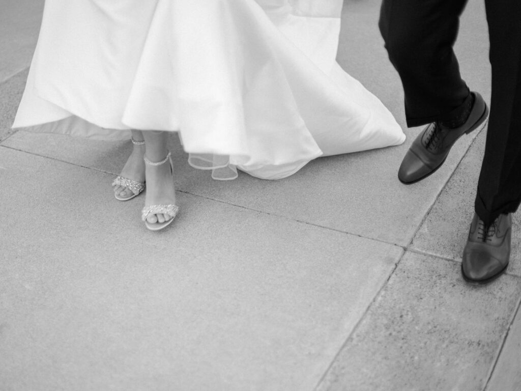 Picture of just the shoes of bride and groom while they are walking.