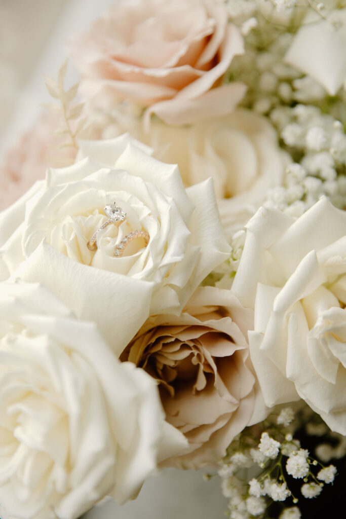 Details of wedding flowers of white and pink roses, babys breath, and rings.