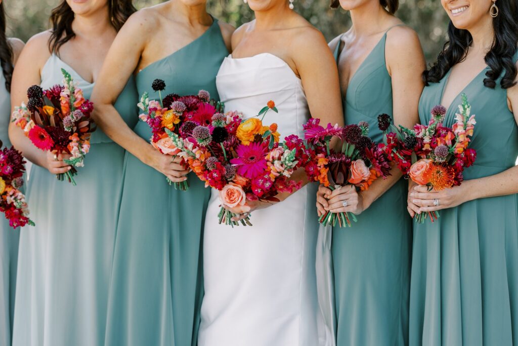 Bridal bouquet detail image of bridal and bridesmaid bouquets of orange, pink and fuchsia colors.