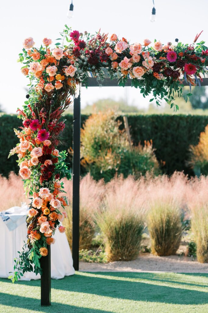 Wedding flowers installed on ceremony chuppah in pink, orange, fuchsia colors.