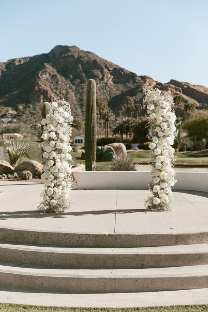 Wedding ceremony floral columns of white roses, mums, and baby's breath.