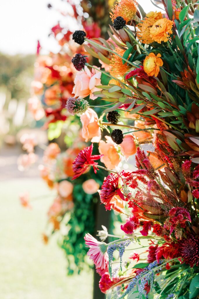 Detail image of wedding chuppah installed flowers in pink, orange, maroon.