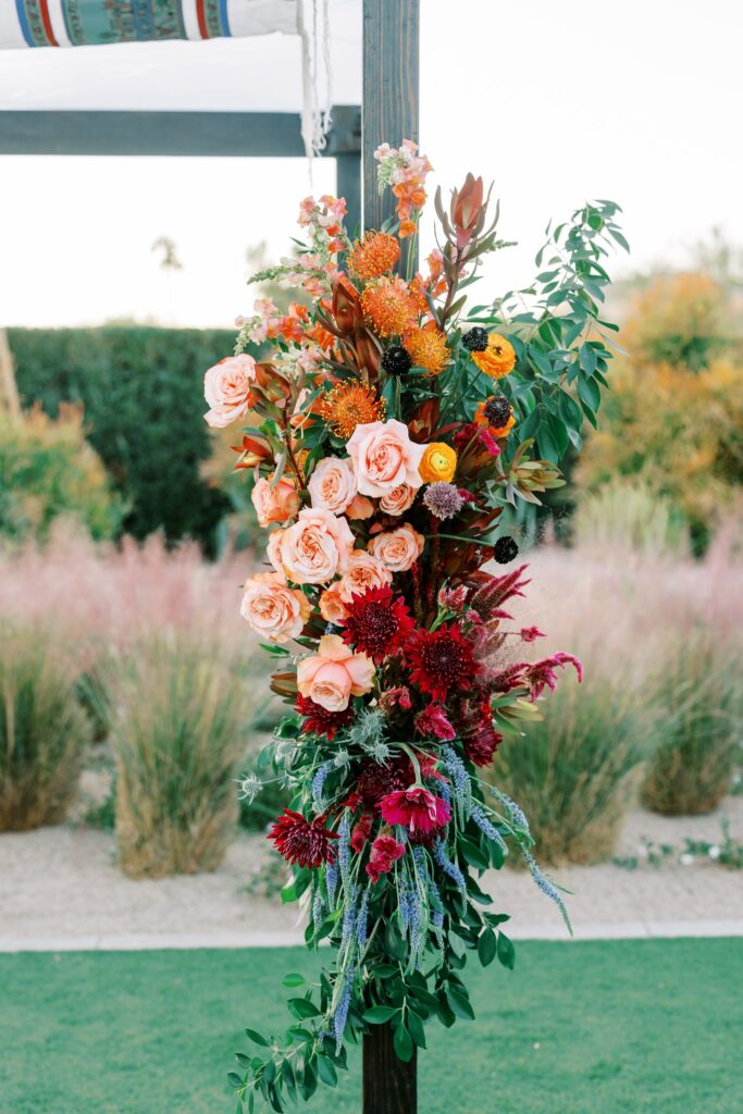 Floral installed on wedding chuppah in pink, orange, fuchsia and greenery.