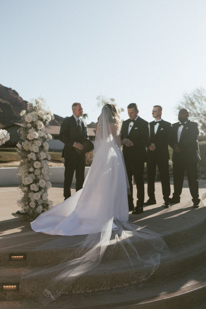 Bride and groom holding hands in outdoor ceremony altar space with officiant standing behind them.