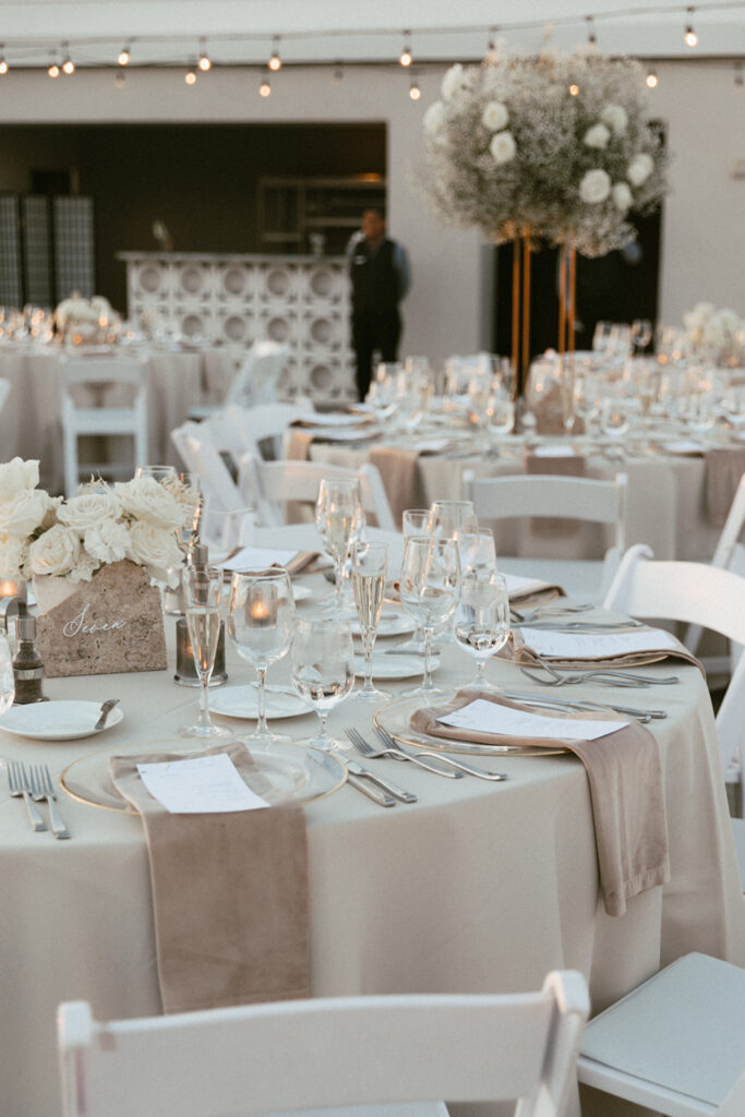 Wedding reception tables of high and low centerpieces of white flowers at Mountain Shadows.