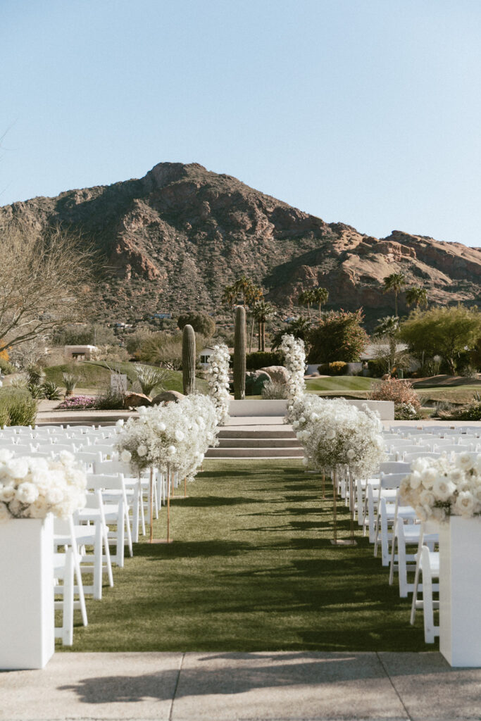 Outdoor wedding ceremony space at Mountain Shadows with back of aisle floral on acrylic columns, tall arrangements on gold stands down the aisle and two floral columns in the altar space.