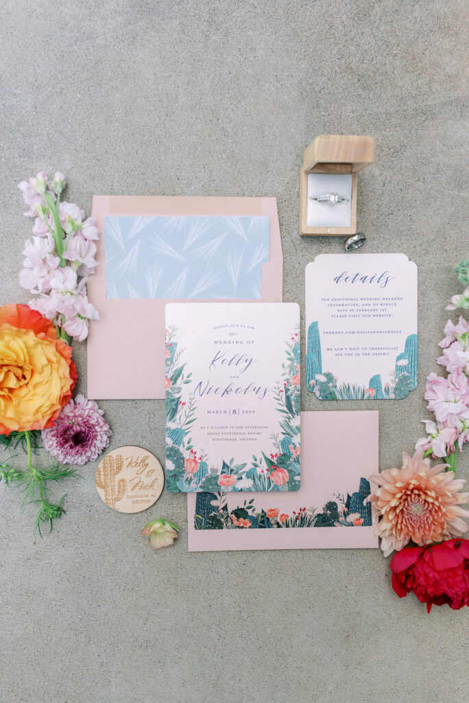 Wedding invitation flat lay with a desert theme with pink and green colors.