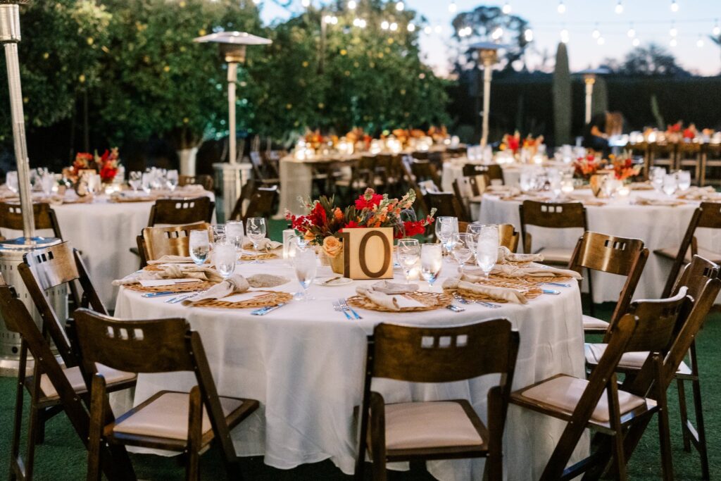 Round reception tables with place settings and low floral centerpieces in center.