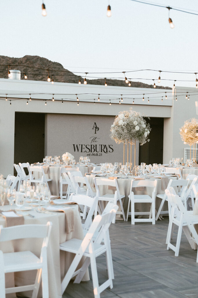 Outdoor Mountain Shadows wedding reception on patio with round tables with high and low centerpieces of white flowers.