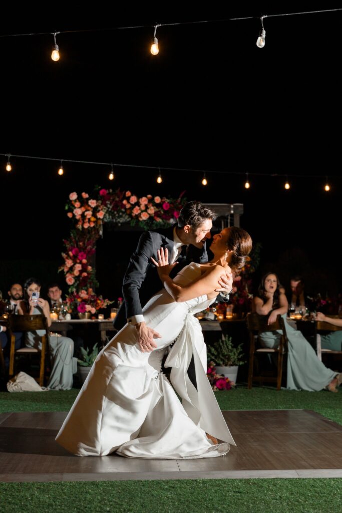 Groom dipping bride during wedding reception dance.