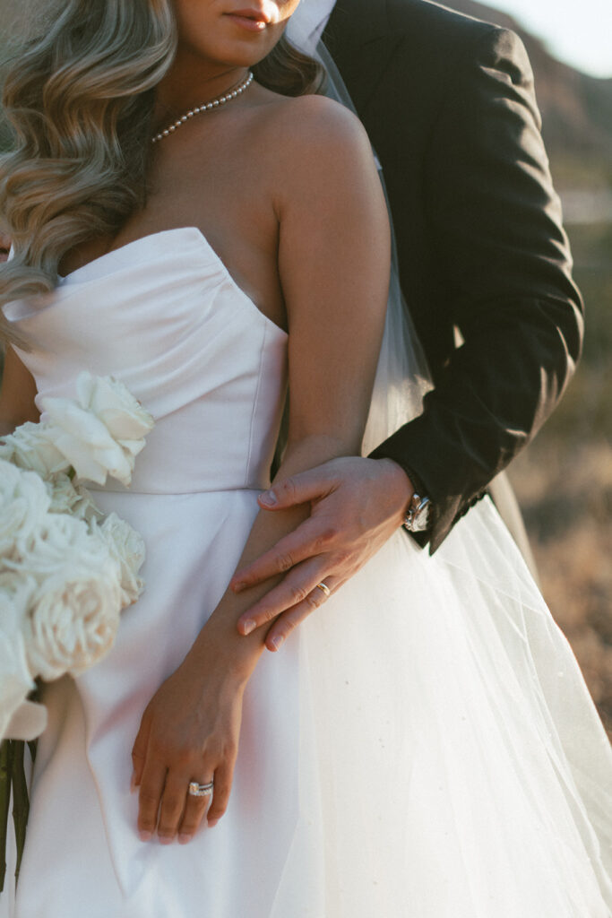 Groom with hand lighting resting on top of bride's arm.