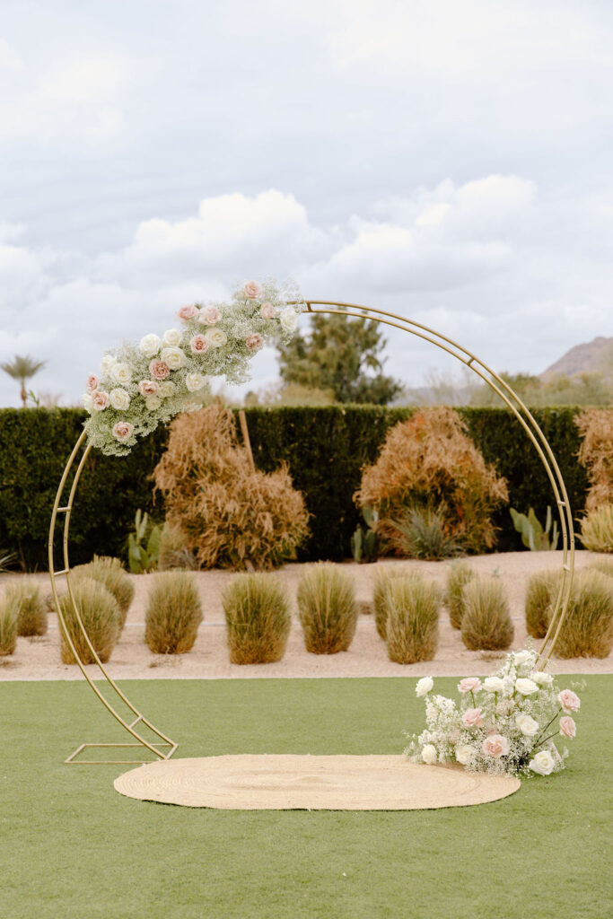 Wedding circle gold arch with floral installed in asymmetrical spacing.