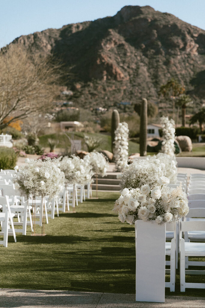 Outdoor wedding ceremony space at Mountain Shadows with back of aisle floral on acrylic columns, tall arrangements on gold stands down the aisle and two floral columns in the altar space.