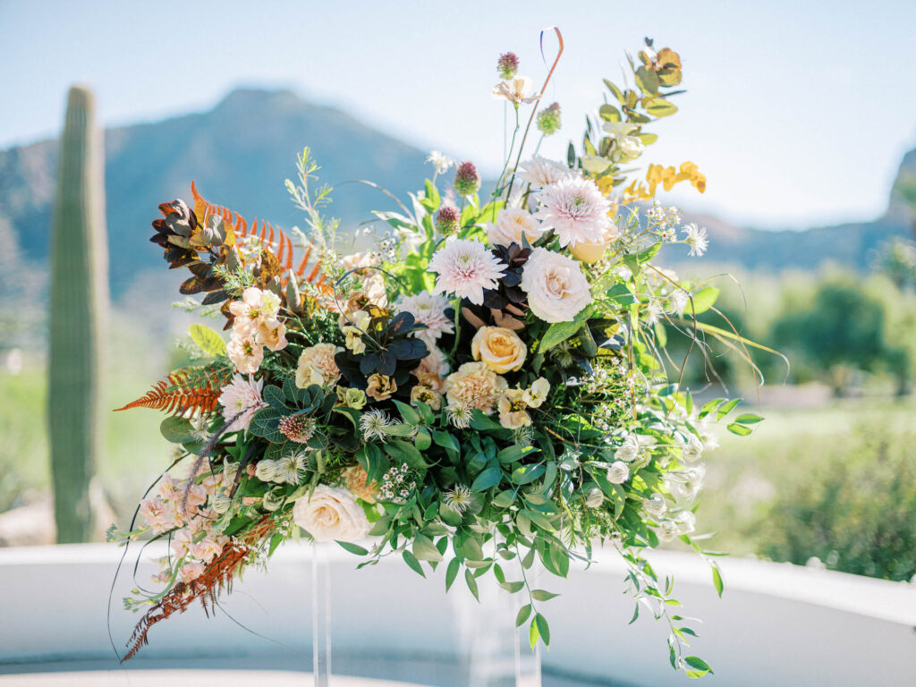 Wedding ceremony floral arrangement of pink, white and soft peach flowers with greenery.