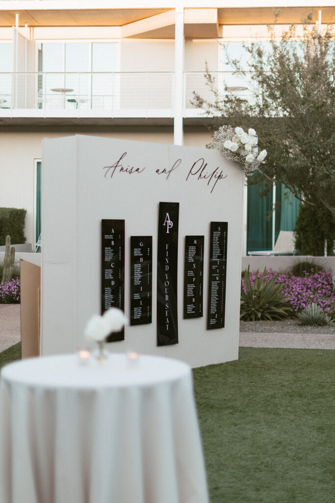 Custom escort board at wedding reception with white roses and baby's breath accent added to top right.