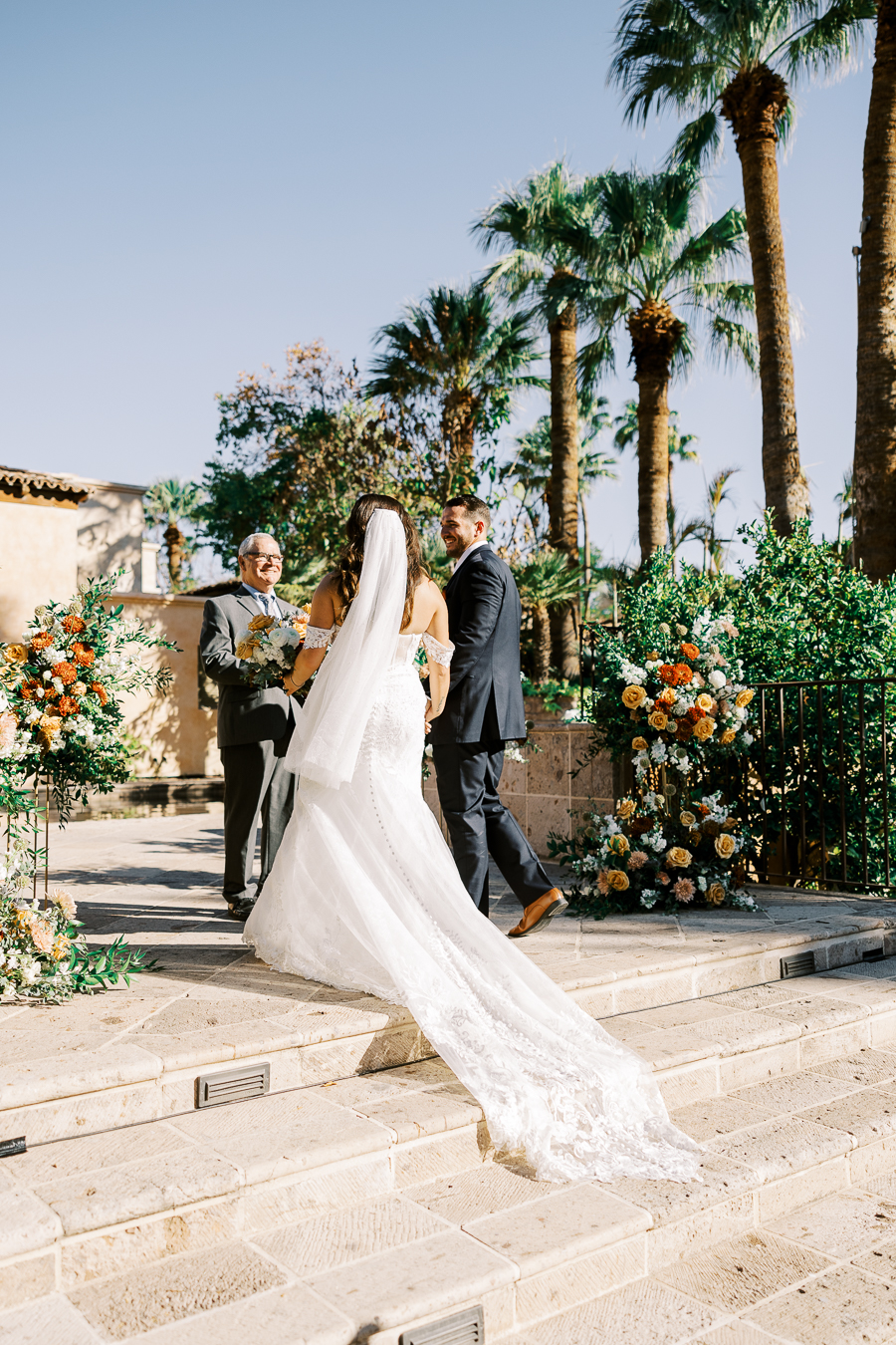 Bride and groom walking up stairs to officiant at altar space at wedding ceremony.