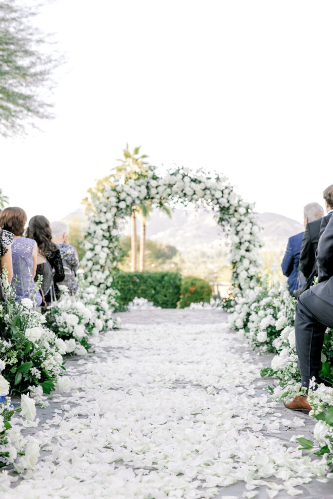 Outdoor wedding ceremony aisle at Sanctuary resort with white rose petals covering it.