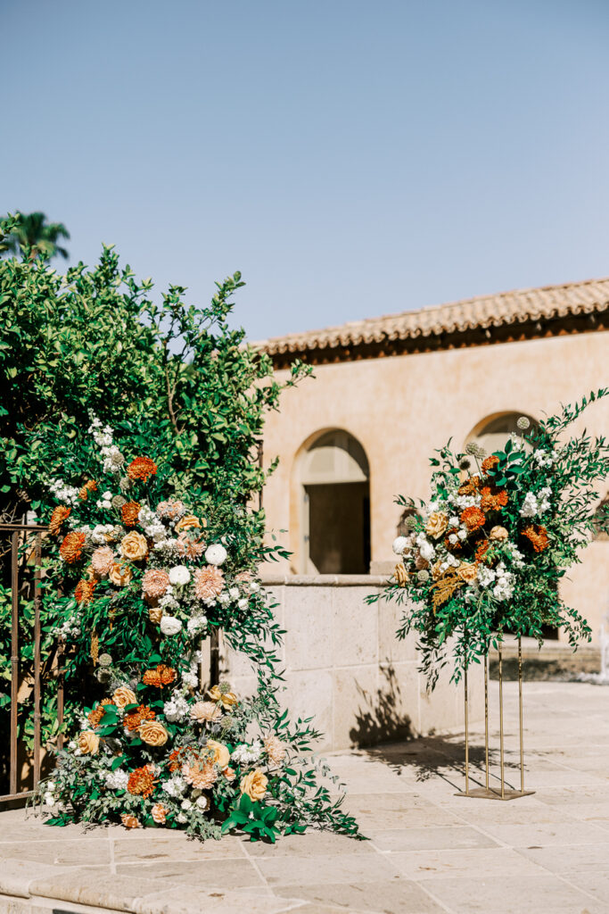 Wedding floral in altar space of orange, gold, and white colors.