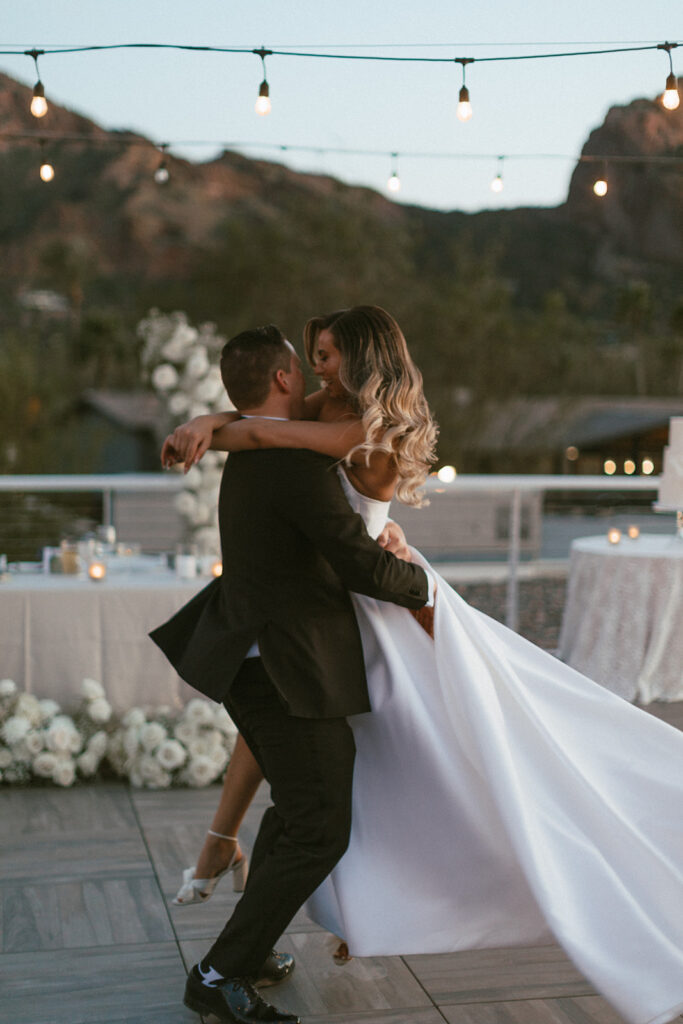 Groom lifting bride up during wedding reception dance.