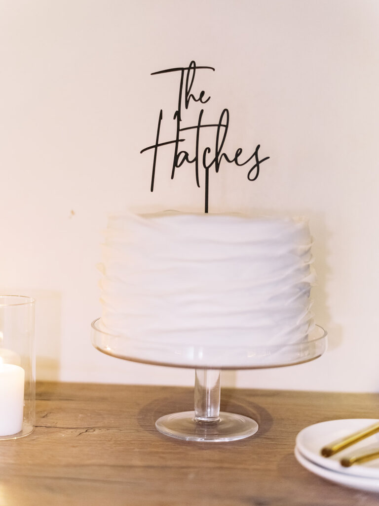 White single tiered wedding cake with topper of their name.