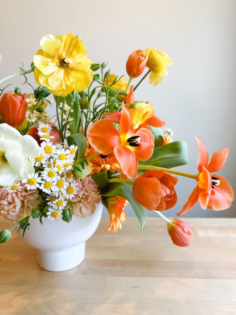 Colorful flowers in a summer-style arrangement in a white vase.