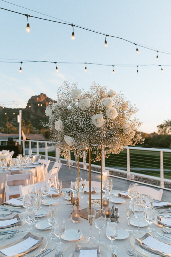 Tall reception centerpiece on gold stand of white roses and baby's breath.