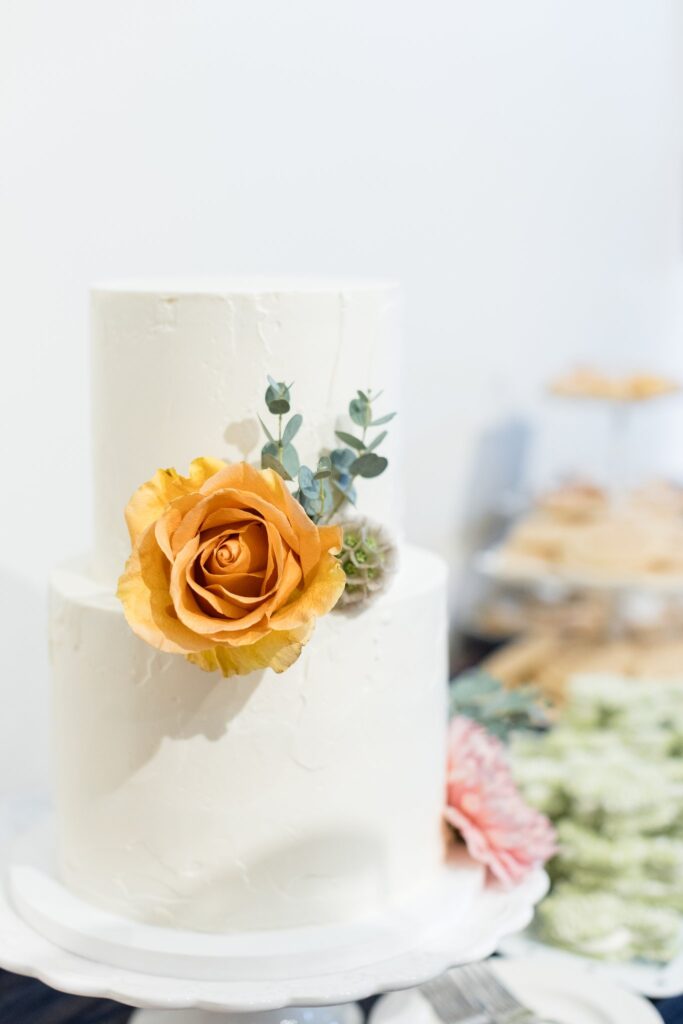 Gold and pink floral with greenery added to two tiered white wedding cake.