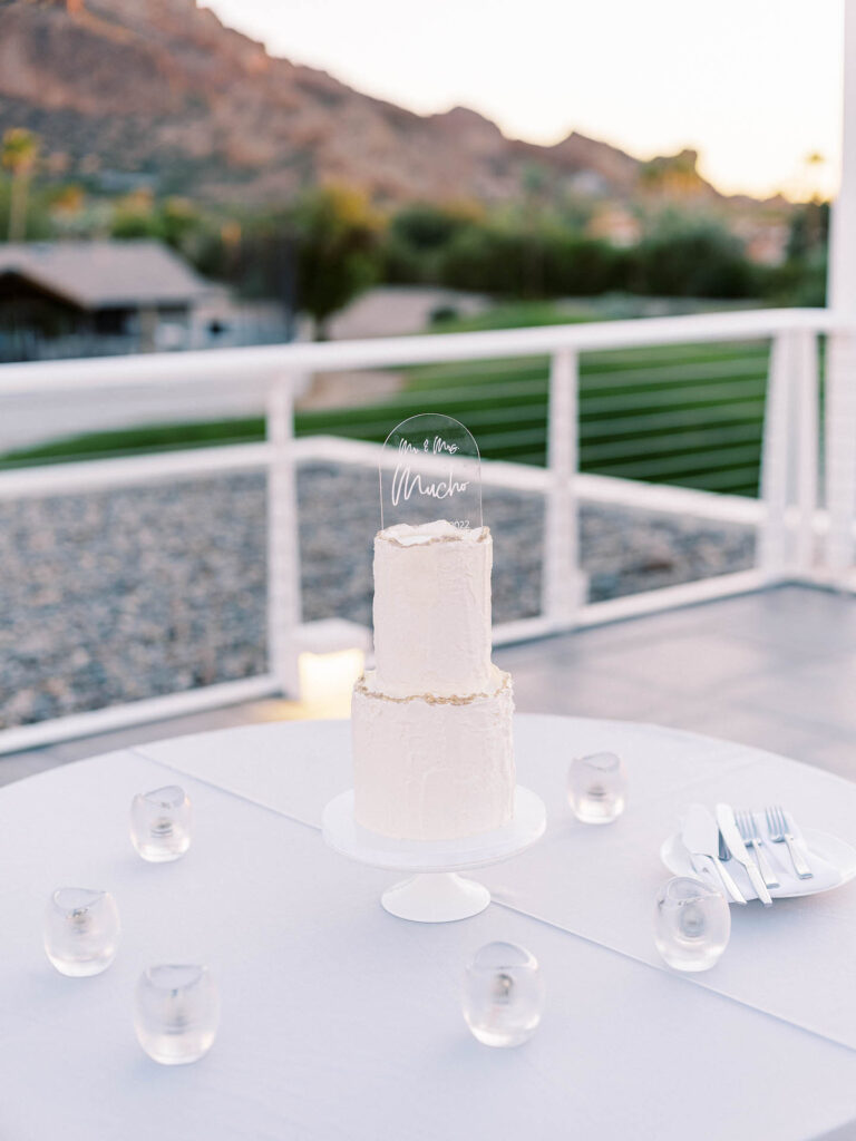 Two tiered white wedding cake on a table.