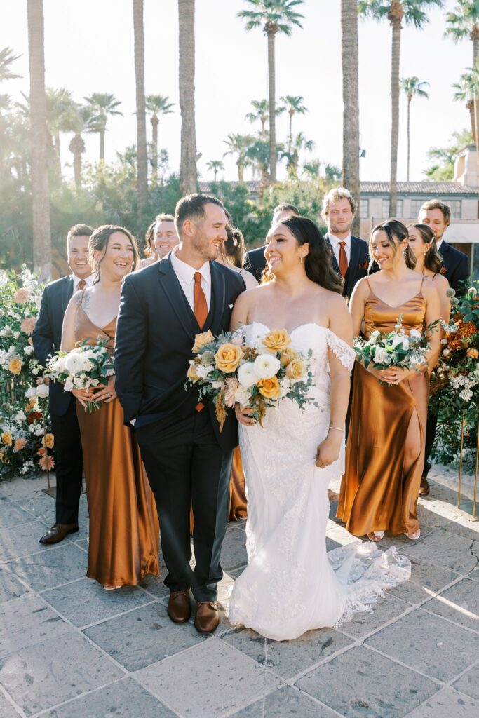Bride and groom standing in front of wedding party behind them.