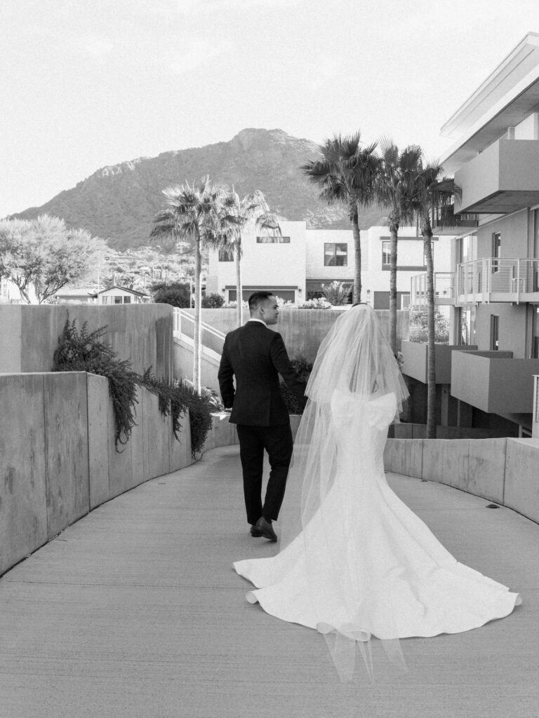 Bride and groom holding hands and walking away down walkway