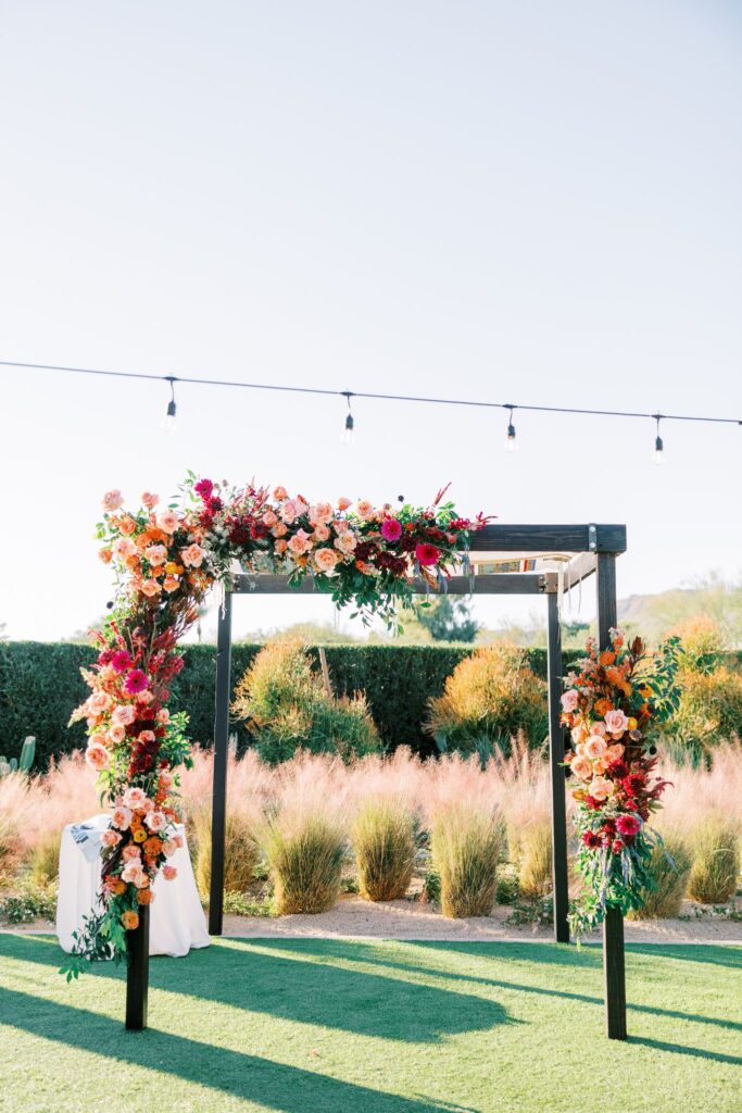 Wedding ceremony chuppah with floral installed on it in colors of pink, orange, and fuchsia.