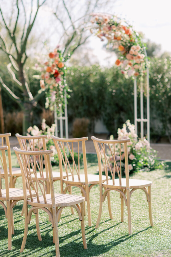 Empty wedding ceremony chairs with ceremony arch in the background.