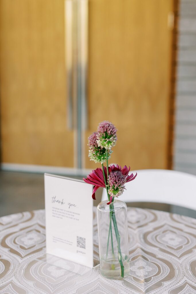 Bud vase of glass with pink flowers in it.