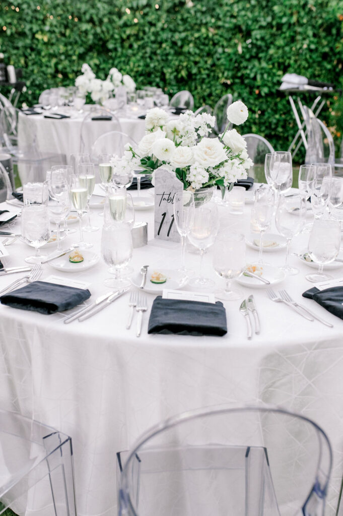 Wedding reception table with white and black linens and white flowers centerpiece in center.