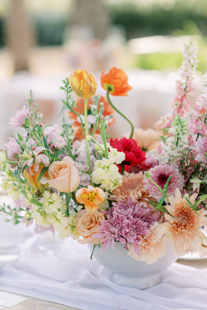 Wedding reception centerpiece in peach, purple, pink, and yellow flowers.