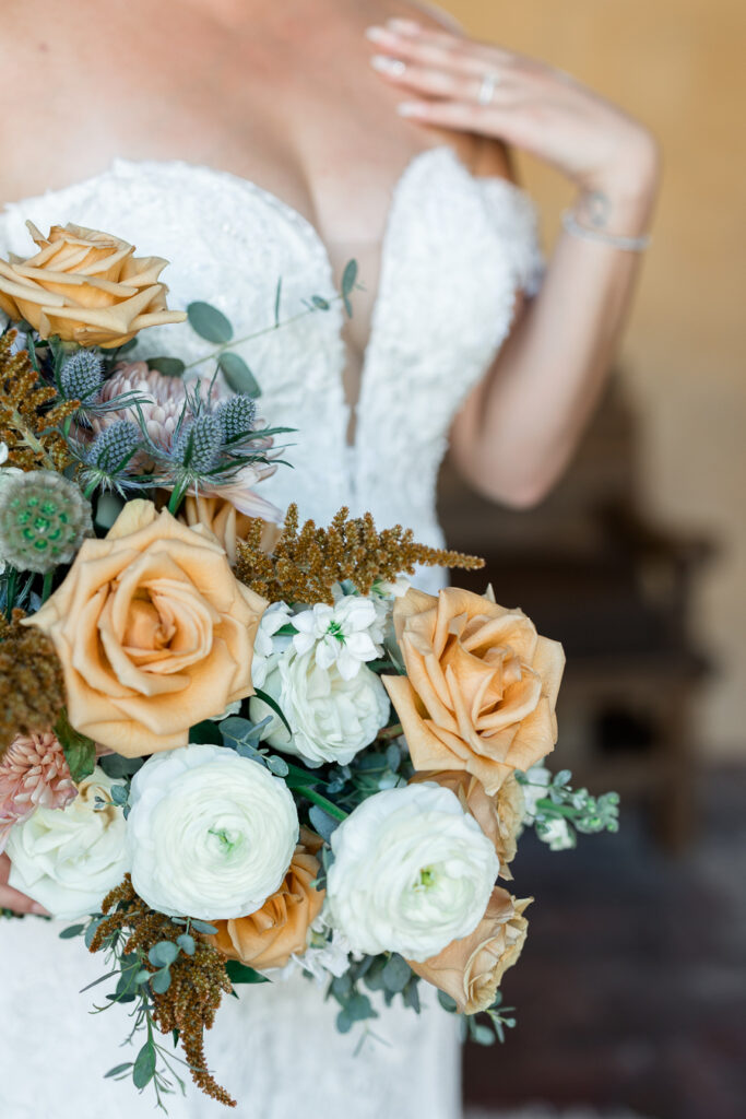 Bridal bouquet floral details or orange roses and other white, pink, and gold flowers.