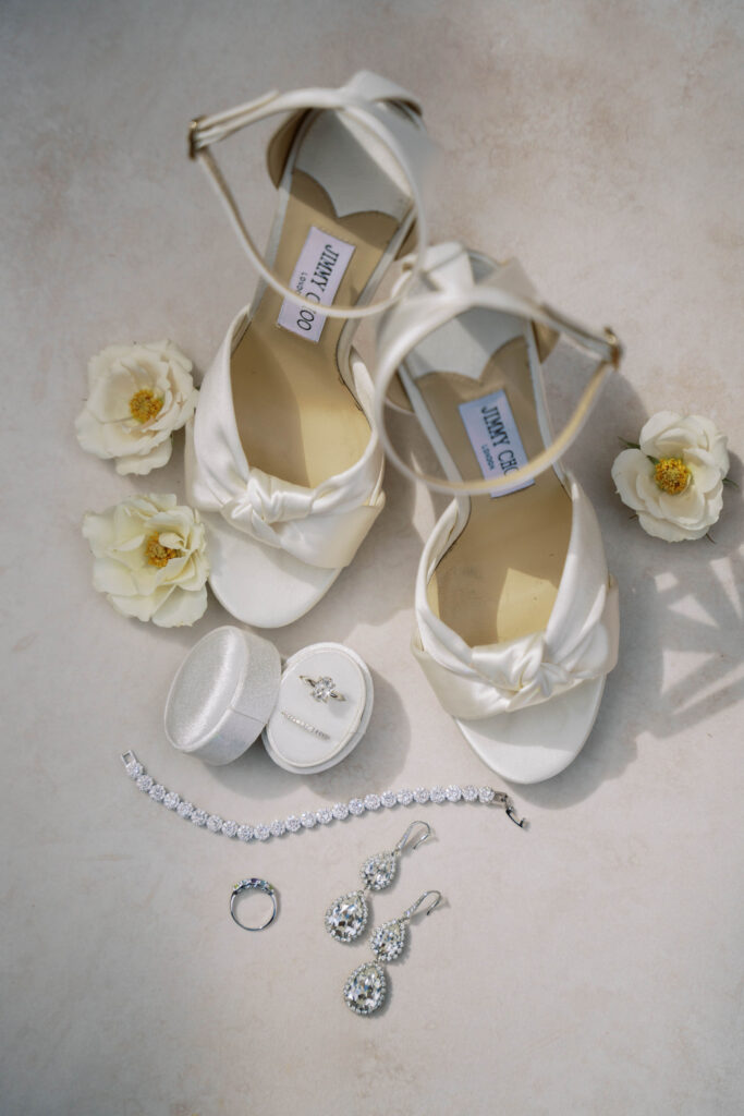 Bridal details of white shoes, rings, bracelet, and earrings.