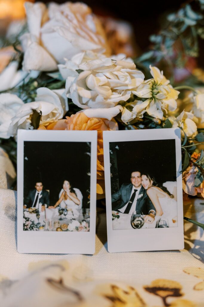 Polaroid photos of bride and groom at wedding resting on flowers behind it.