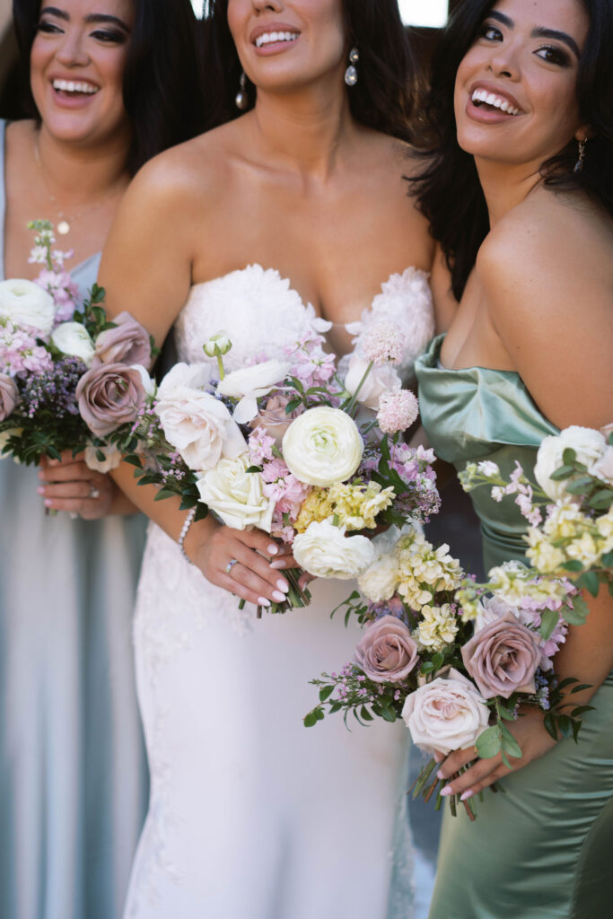 Bride and bridesmaids smiling, holding bouquets.