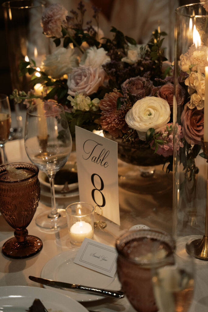 Evening wedding reception with taper candles and white, pink, mauve colored flowers centerpice.