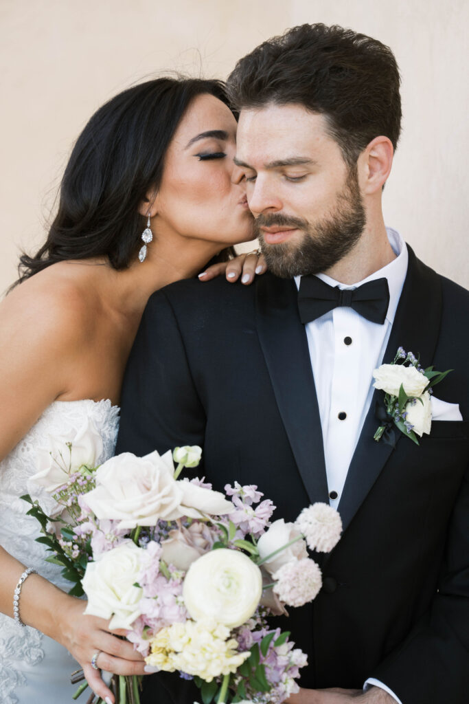 Bride kissing groom on cheek.