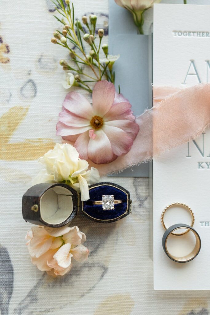 Details flat lay of wedding rings and invitation.