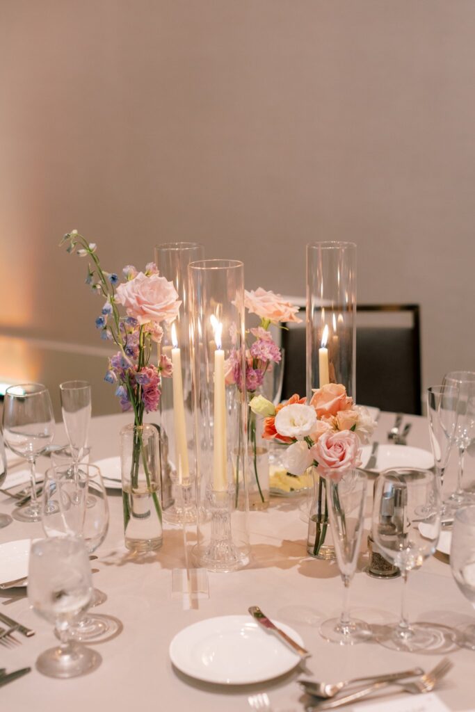 Wedding reception floral centerpiece design of bud vases and taper candles.