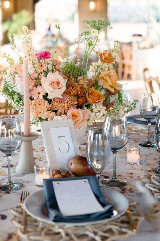 Wedding reception centerpiece of white, pink, gold, peach, and mauve flowers.