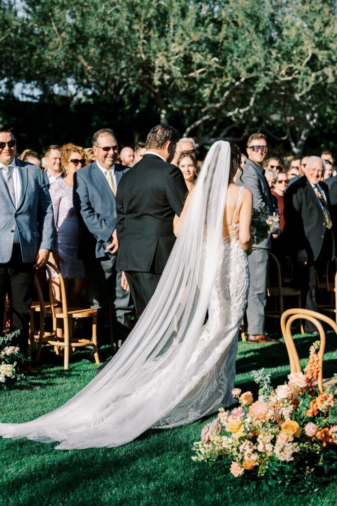 Bride walking down aisle of wedding ceremony with man.