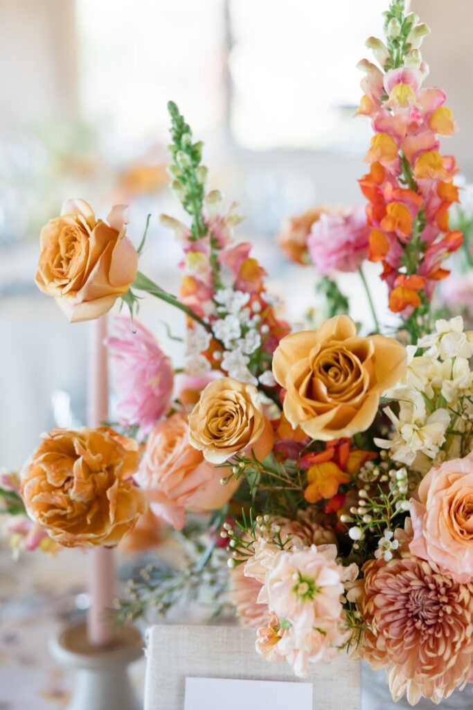 Wedding flowers in gold, pink, and peach colors in reception centerpiece.